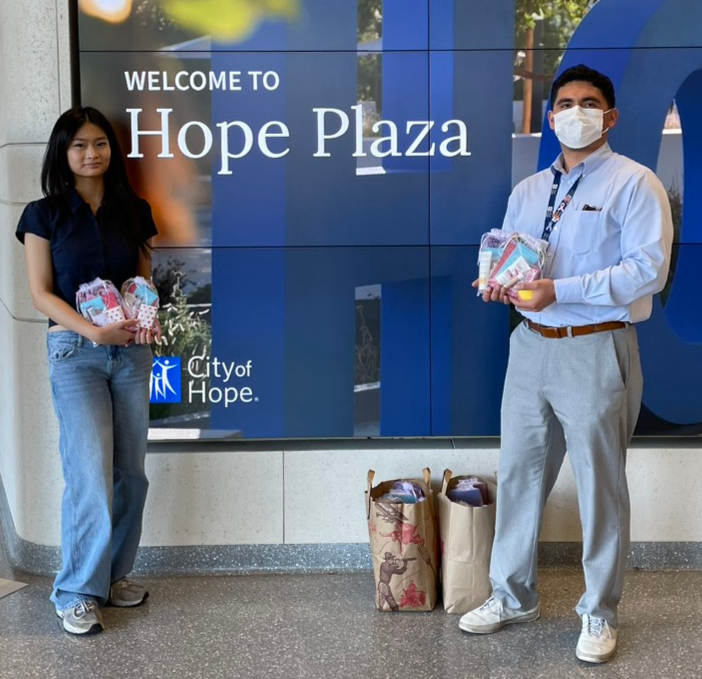 A Heart in Hand volunteer and a City of Hope staff member holding care kits
