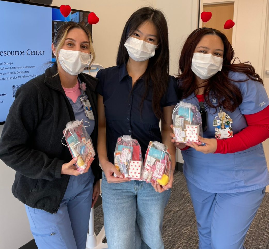 A Heart in Hand volunteer with two City of Hope staff members holding care kits